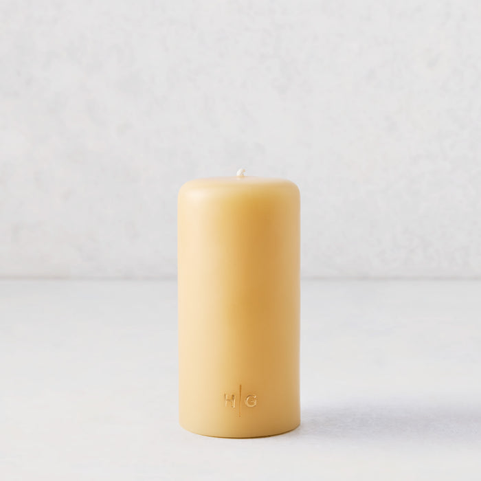 3x6 inch amber pillar candle with a gold HG logo, hand-dipped paraffin wax, and a cotton wick.