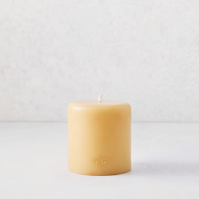 4x4 inch amber unscented pillar candle with a gold HG logo, hand-dipped from natural paraffin and tree resin.