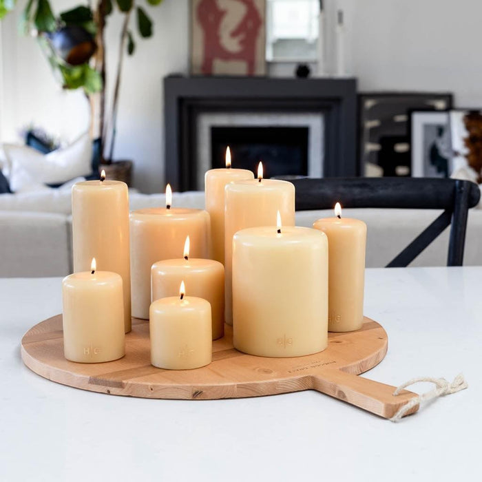 HG Amber Unscented Pillar Candle, 4"x4", hand-dipped paraffin, with gold HG logo, on a wooden tray.