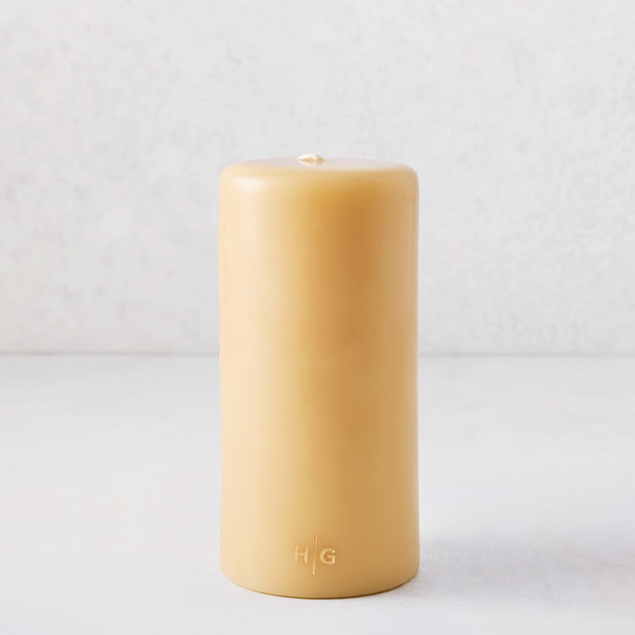 4x8 inch amber unscented pillar candle with a gold HG logo embossed on all-natural paraffin wax.