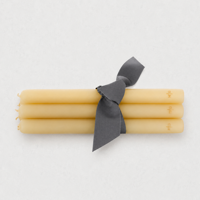 Set of five 12-inch amber unscented taper candles with a gold HG logo, tied together with a grey ribbon.