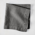 Asphalt HG Signature hand-dyed linen napkin, 22-inch square, folded, dark gray with visible texture.