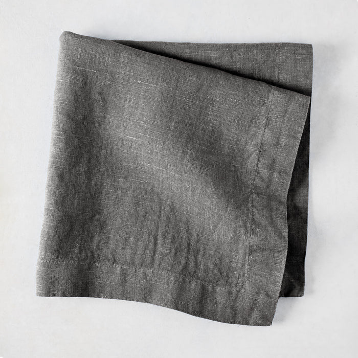 Asphalt HG Signature hand-dyed linen napkin, 22-inch square, folded, dark gray with visible texture.