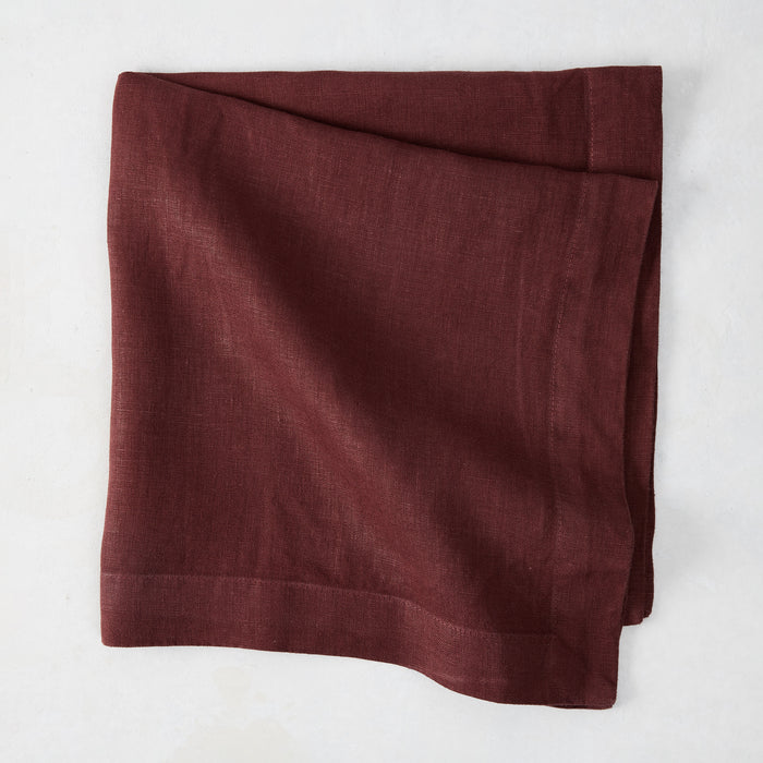 Barnwood HG Signature hand-dyed 22-inch maroon linen napkin, folded on a white surface.