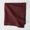 Barnwood HG Signature hand-dyed 22-inch maroon linen napkin, folded on a white surface.