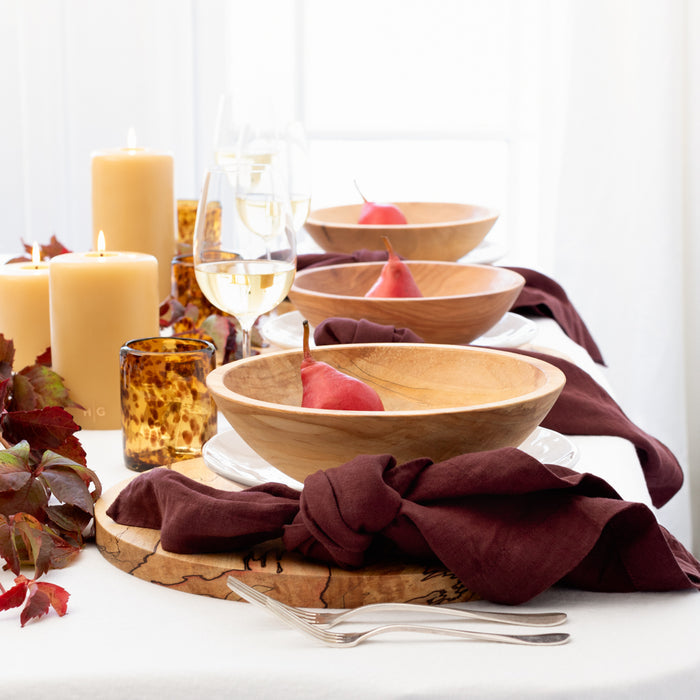 Barnwood HG Signature Hand-dyed Linen Napkin in a knot, styled with wooden bowls and red pears on a table.