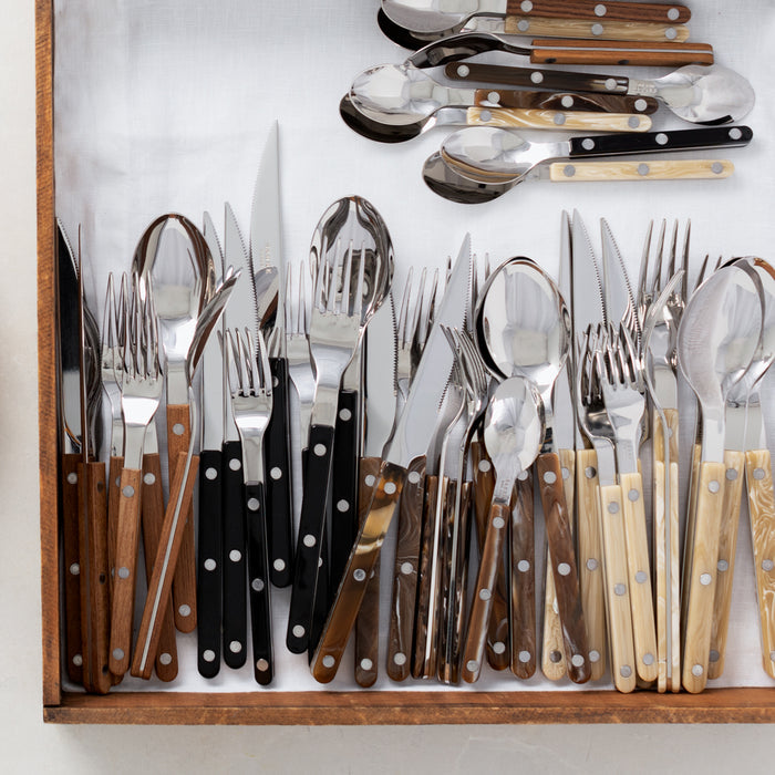 Assorted French bistro flatware sets with stainless steel and acrylic handles in black, brown, and cream.