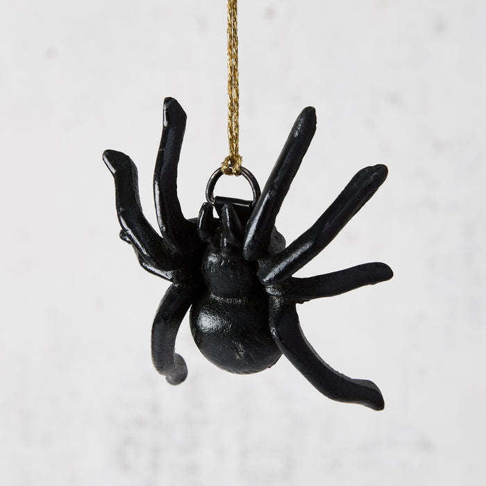 Black cast iron decorative spider, 3"L x 3.5"W, hanging by a gold string.