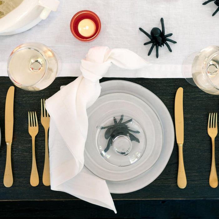 Black cast iron decorative spider on a white plate with gold cutlery.