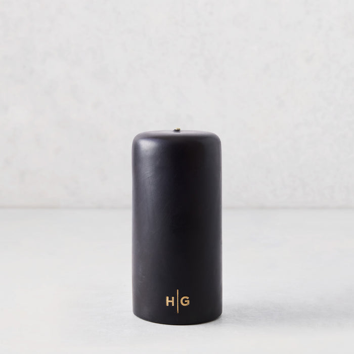 3x6 inch black hand-dipped pillar candle with a gold HG logo on a light background.