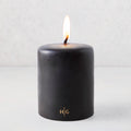 5x6 inch black hand-dipped pillar candle with a burning wick and gold HG logo on a light gray background.