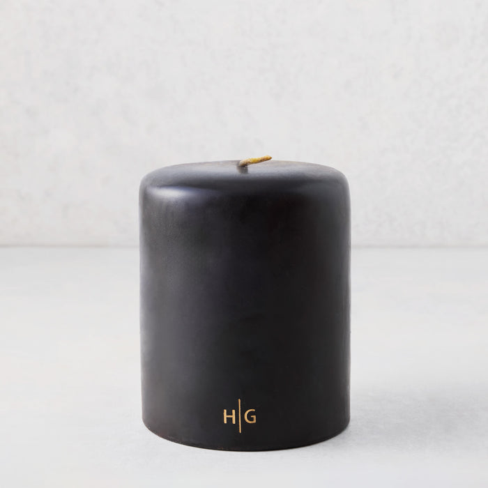 5x6 inch black hand-dipped pillar candle with gold HG logo and cotton wick.