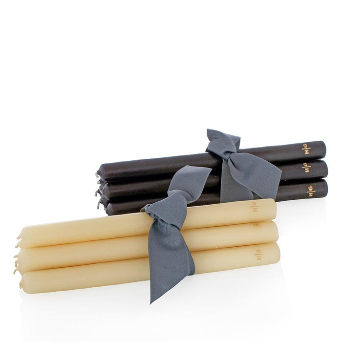 Two bundles of 10" taper candles, one black and one cream, tied with gray ribbons.