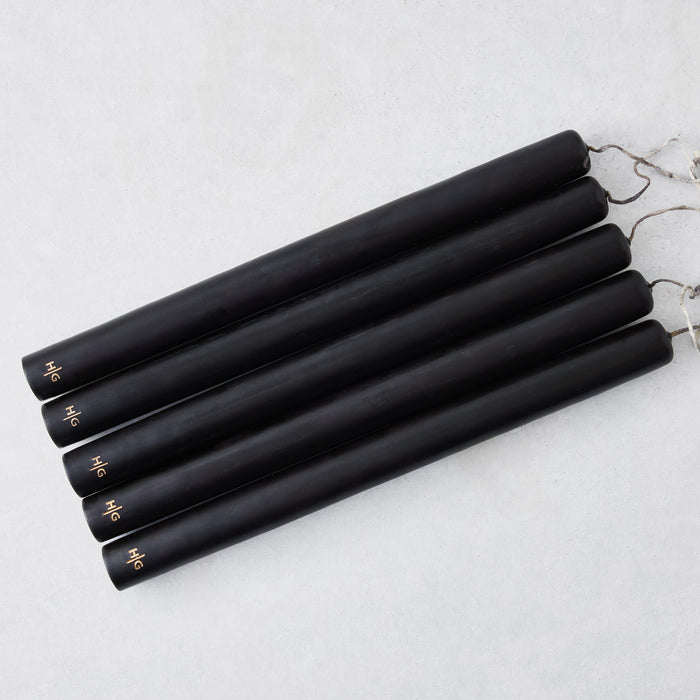Set of five 12-inch black hand-dipped taper candles with gold HG logo embossed on each base.