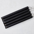 Set of five 12-inch black hand-dipped taper candles with gold HG logo embossed on each base.