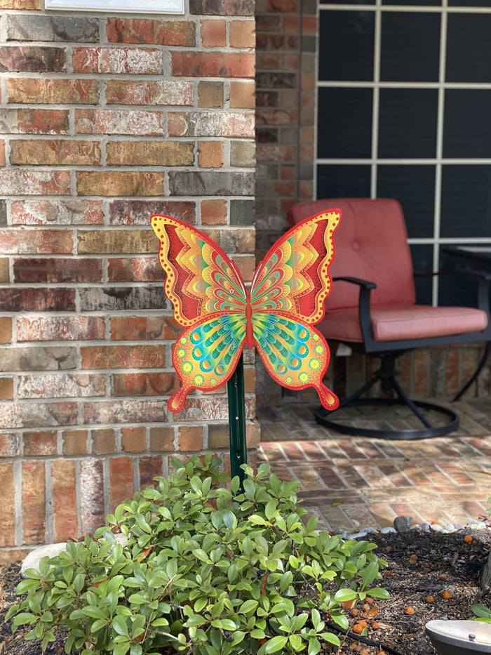 Butterfly wooden yard art sign next to a front porch in a homeowners yard. Brighten up your front lawn with butterfly decorations from Yard Art Decor and More.