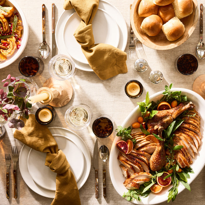 White ceramic deep serving platter with roasted turkey, oranges, and herbs.