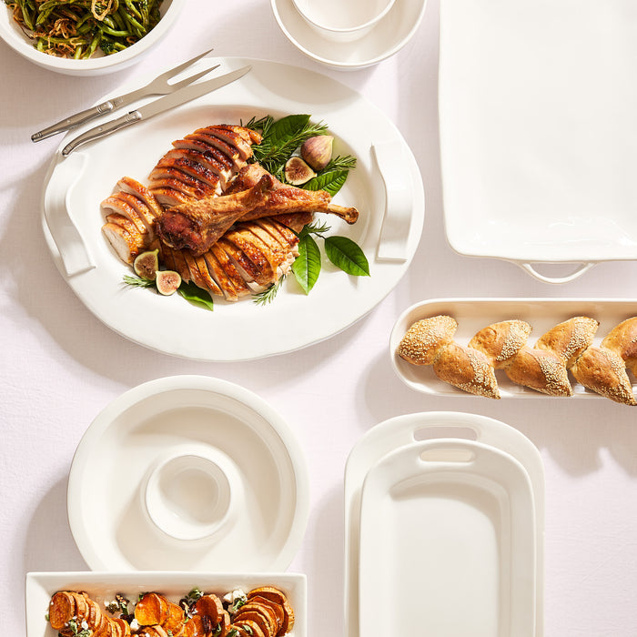White ceramic handled serving platter with carved turkey, figs, and rosemary.