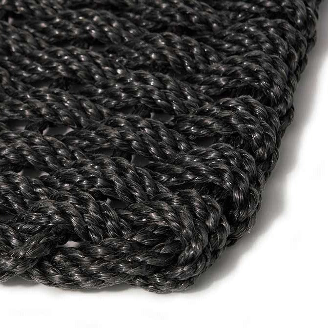 Close-up of a handwoven charcoal braided rope doormat, showing its textured, durable weave.