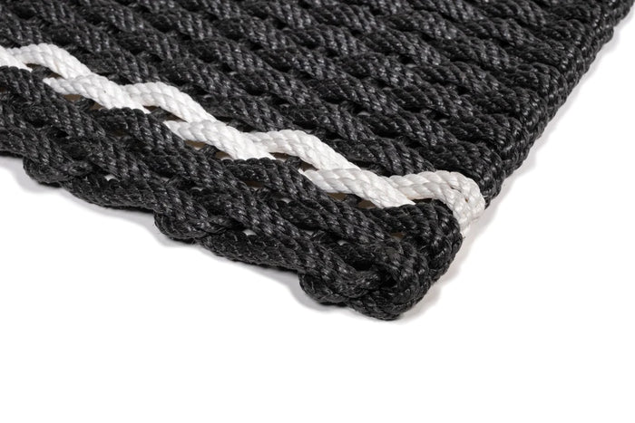 Handwoven charcoal rope doormat with a white pearl stripe, showing its braided texture.