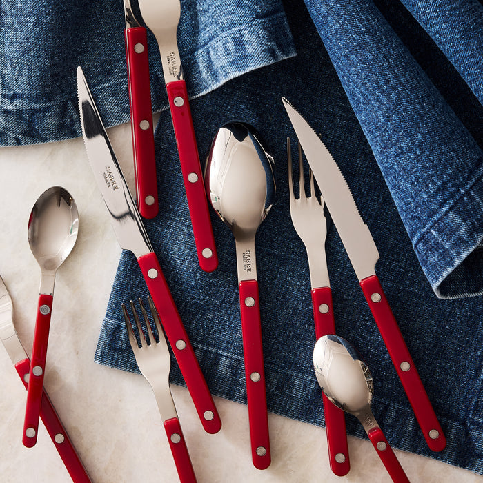 Cherry red acrylic handle 5-piece Bistro flatware set with stainless steel, on a blue denim napkin.