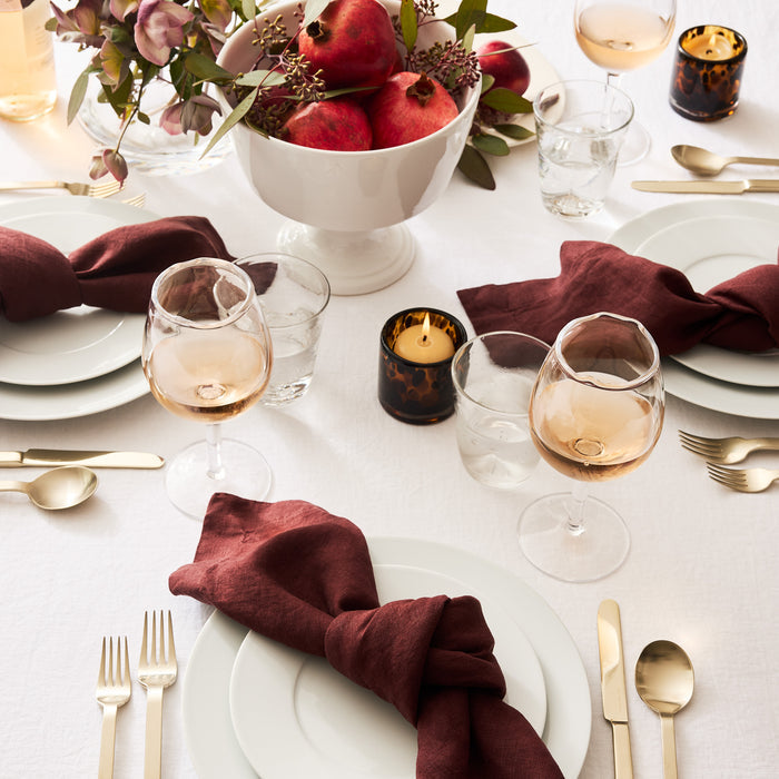 White HG Classic Porcelain Dinner Plate set on a table with burgundy napkins, gold flatware, and wine glasses.
