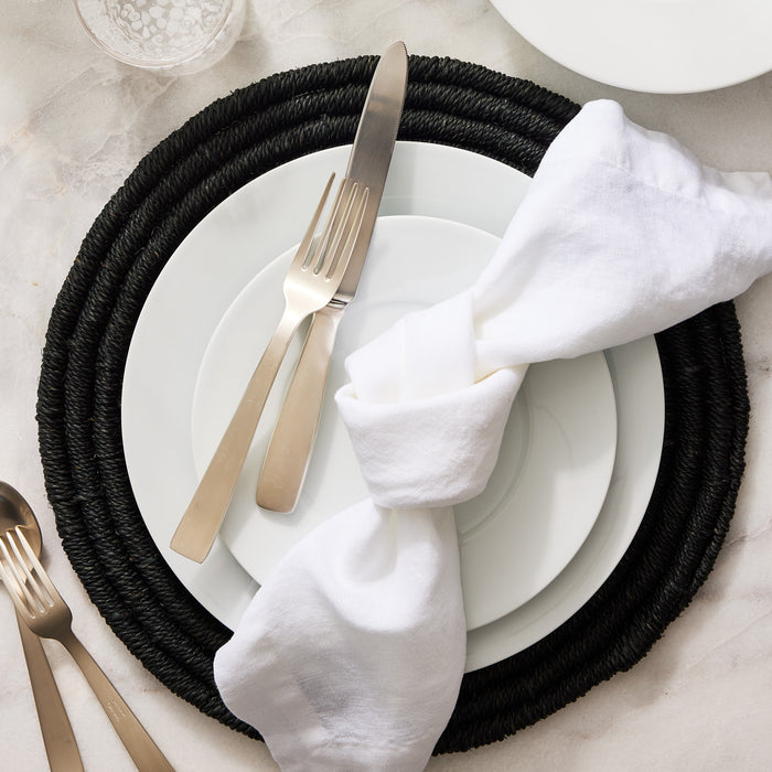 White HG Classic Porcelain Dinner Plate on a black woven placemat with silverware and a white linen napkin.