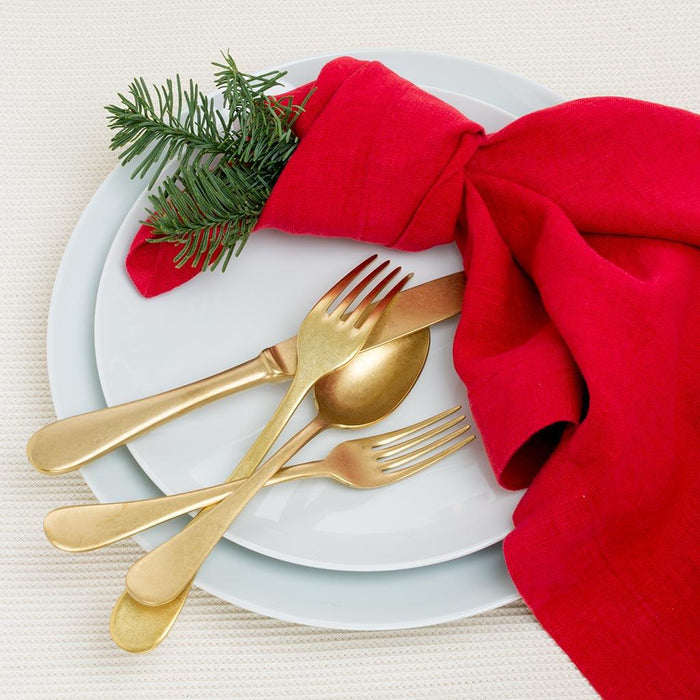 White HG Classic Porcelain Dinner Plate with gold flatware, red napkin, and pine sprig.