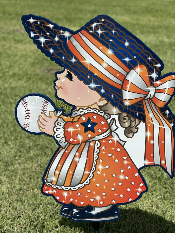 Outdoor yard decor sign of a little girl in a dress with stars and a hat with stars and stripes holding a baseball.  Baseball themed outdoor yard decor and lawn signs available at Yard Art Decor and More.
