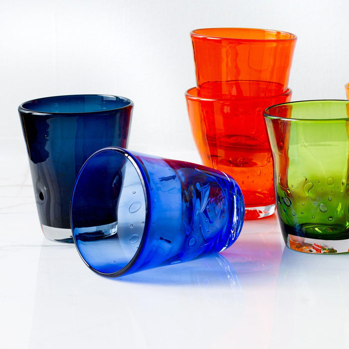 Dark blue Henri 8 oz. mouth-blown glass with visible air bubbles, surrounded by other colorful glasses.