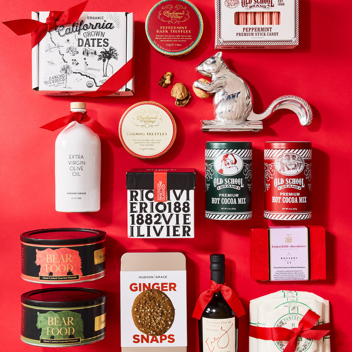 Silver squirrel nutcracker surrounded by various gourmet food products and gifts on a red background.