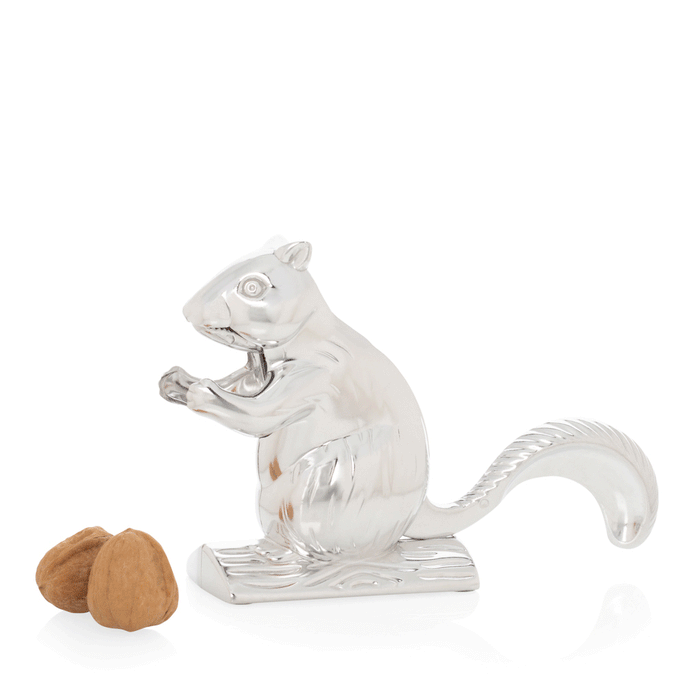 Shiny silver metal squirrel nutcracker with two walnuts beside it.