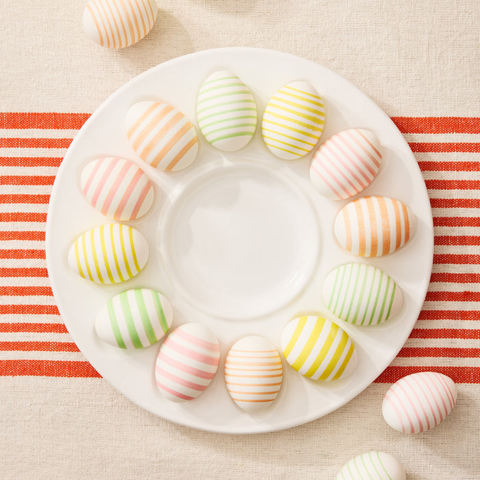 White ceramic Deviled Egg Serving Platter, 11"Dia, holding a dozen pastel striped decorative eggs.
