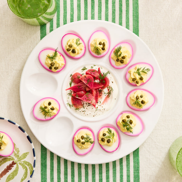 White ceramic Deviled Egg Serving Platter, 11"Dia, holding twelve pink-rimmed deviled eggs with a center dip.