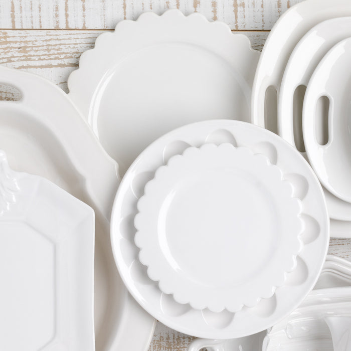 White ceramic deviled egg platter with scalloped edges, 11" diameter, shown among other white serveware.