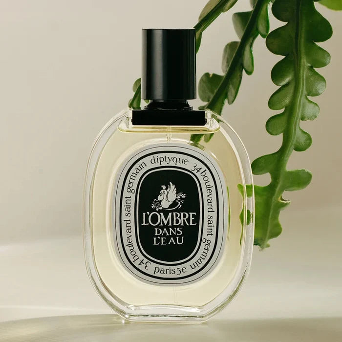 Diptyque perfume bottle with a plant leaf on a neutral background