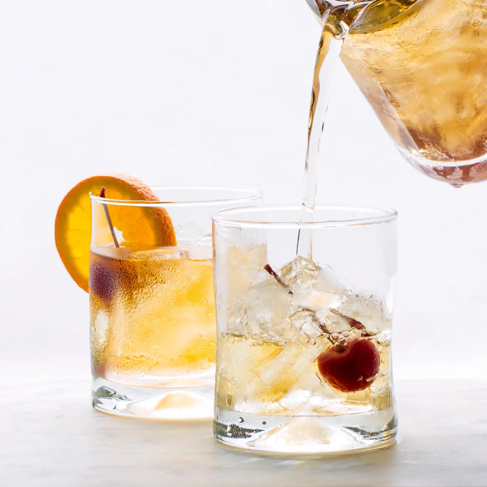 Hudson Grace Double Old-Fashioned Glass, clear glass with heavy base, being filled with a drink.