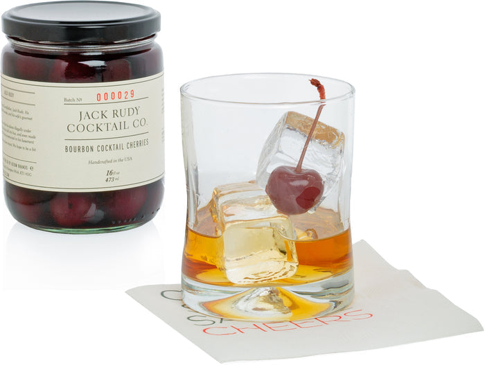 Hudson Grace Double Old-Fashioned Glass with whiskey, ice, and cherry, next to a jar of bourbon cocktail cherries.