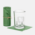 Roll of 50 eucalyptus green cotton cocktail napkins with white stitching, next to a glass with ice on a single napkin.