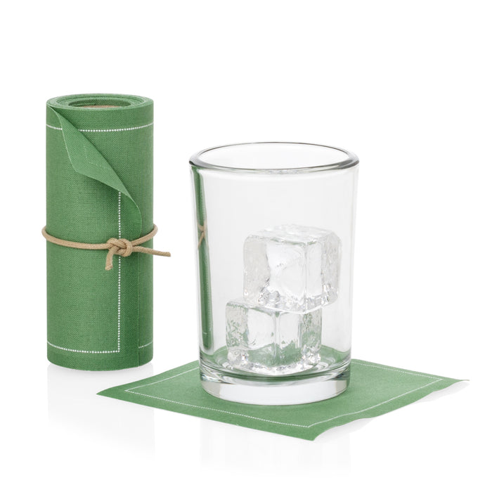 Roll of 50 eucalyptus green cotton cocktail napkins with white stitching, tied with twine, next to a glass with ice on a single napkin.