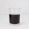 Clear, simple Hudson Grace Everyday Wine Glass filled with red liquid on a white background.