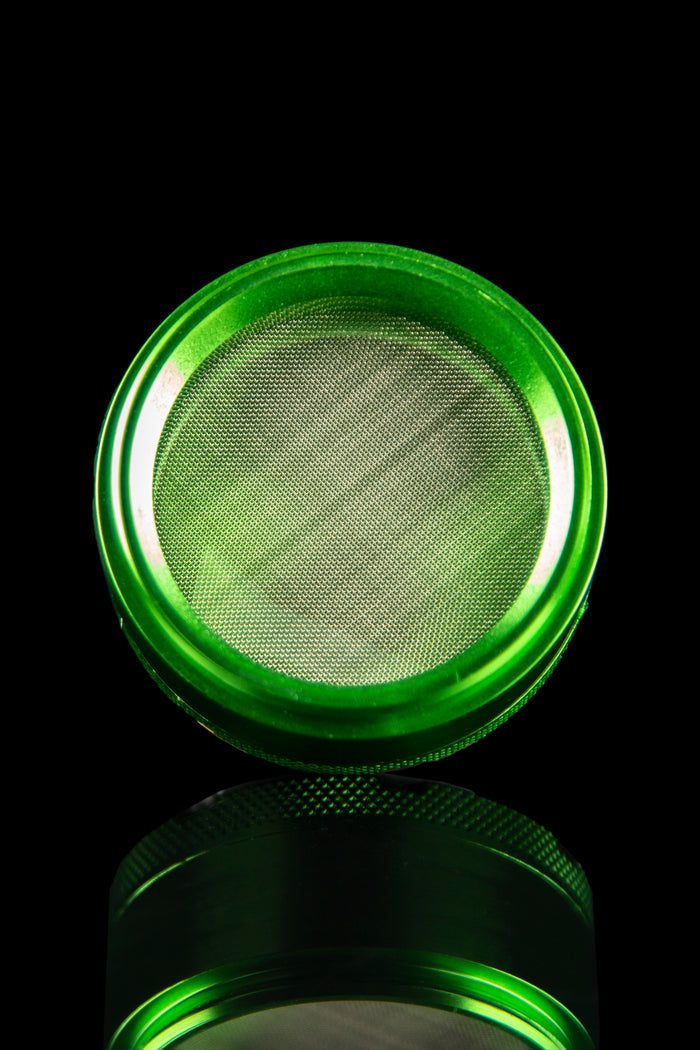 Top-down view of the Famous X 4-Piece Grinder, showcasing the textured metal interior within its circular frame.