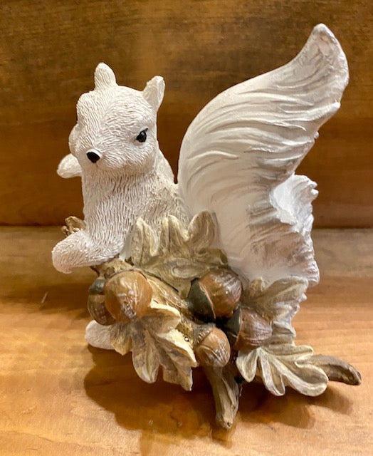 Resin hand painted white squirrel figurine holding a leaf with acorns on it.