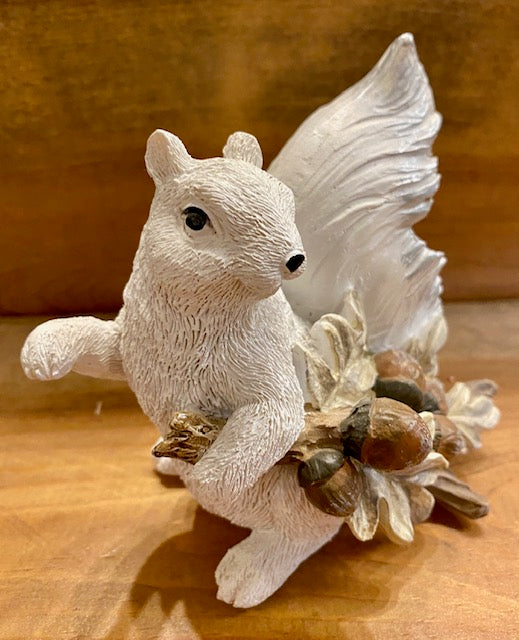 Front view of our hand painted resin white squirrel holding a leaf with acorns.
