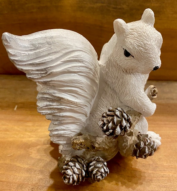 White resin squirrel dragging a branch with pine cones.
