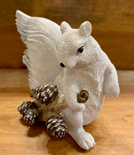 Front view of our resin white squirrel dragging a branch with pine cones.