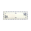 White linen table runner with Blue Onion embroidery, blue onion motifs around the rim, and blue flowers blooming from two corners.
