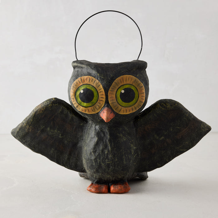 Handcrafted black papier-mâché flying owl Halloween candy bucket with large green eyes and a wire handle.