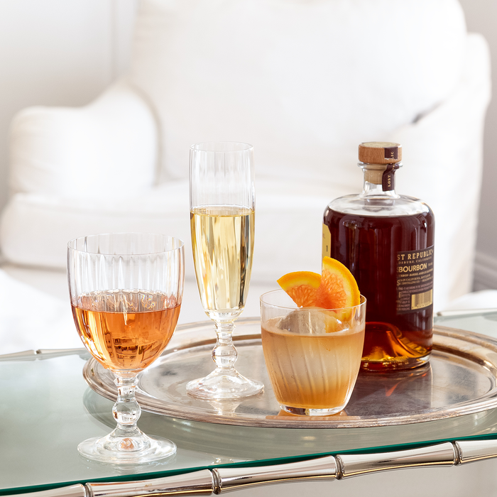 Georgia Eco-Crystal Champagne Glass, 8oz, with ribbed design, next to a wine glass and bourbon cocktail.