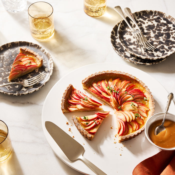 Gio Ponti satin silverplate cake server with a tart, plates, and drinks on a marble surface.